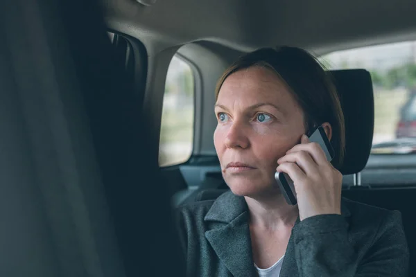 Mujer de negocios hablando por teléfono móvil en el asiento trasero del coche — Foto de Stock