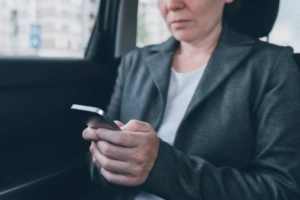 Messaggi di testo di una donna d'affari sul cellulare in auto — Foto Stock
