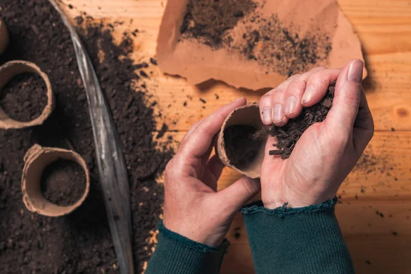 Gardener filling biodegradable soil pot container