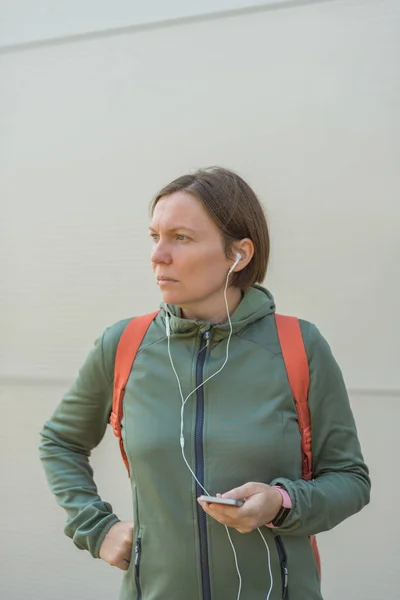 Caminante urbano rápido femenino escuchando música en los auriculares — Foto de Stock