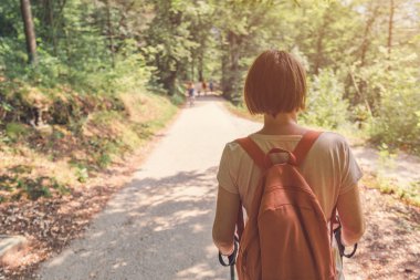 Kadın yürüyüşçü halk parkında yaya yolunda yürüyor.