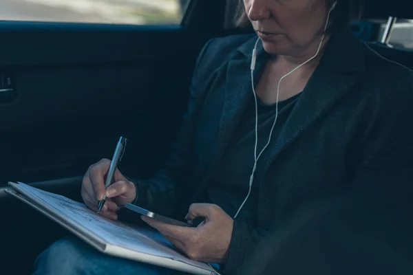 Bizneswoman robi papierkową robotę w samochodzie na tylnym siedzeniu — Zdjęcie stockowe