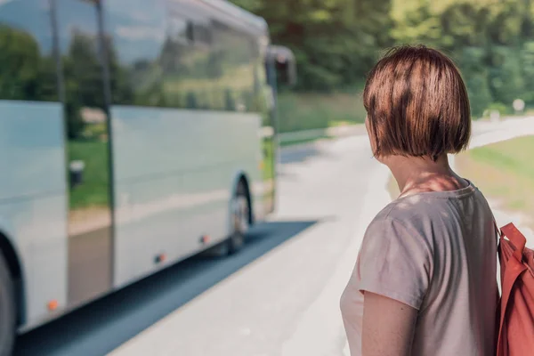 stock image Female hiker looking at bus passing by her