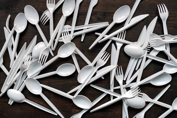 Plastic disposable tableware scattered on wooden table — Stock Photo, Image