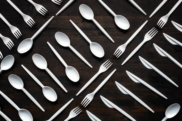 Plastic disposable tableware scattered on wooden table — Stock Photo, Image