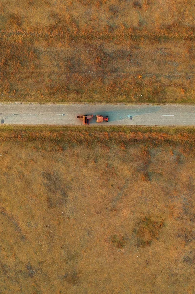 Alter Traktor auf abgefahrenem Asphaltweg durch Grünland — Stockfoto