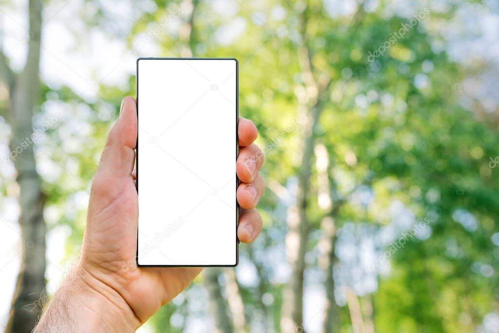 Smartphone screen mock up, man holding modern mobile phone device with blank white screen outdoors in nature