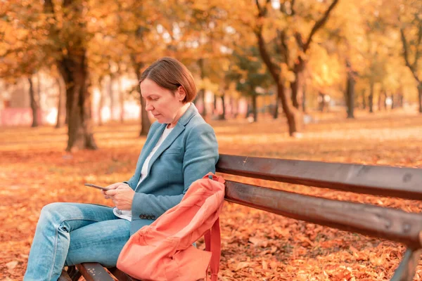 Güneşli Bir Sonbahar Gününde Parkta Bankta Otururken Dinlenirken Cep Telefonu — Stok fotoğraf