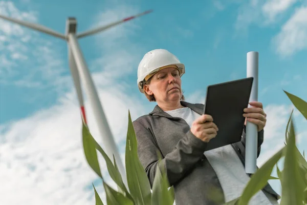 メンテナンスプロジェクト計画中の近代的な風力タービンファーム上のタブレットコンピュータを持つ女性エンジニア — ストック写真