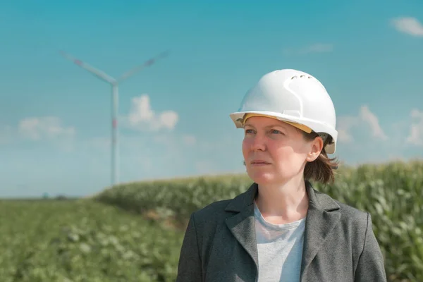 Portrait of female engineer on modern wind turbine farm during maintenance project planning