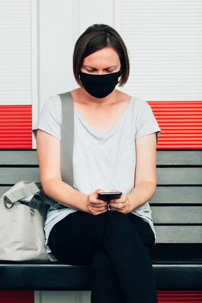 Kobieta Maską Ochronną Wpisując Sms Smartfonie Siedząc Miejskiej Ławce Ulicznej — Zdjęcie stockowe