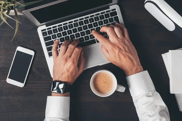 デスクでコーヒーを飲みながらノートパソコンのキーボードを入力するビジネスの人の手のオーバーヘッドショット ワークスペースのトップビュー — ストック写真