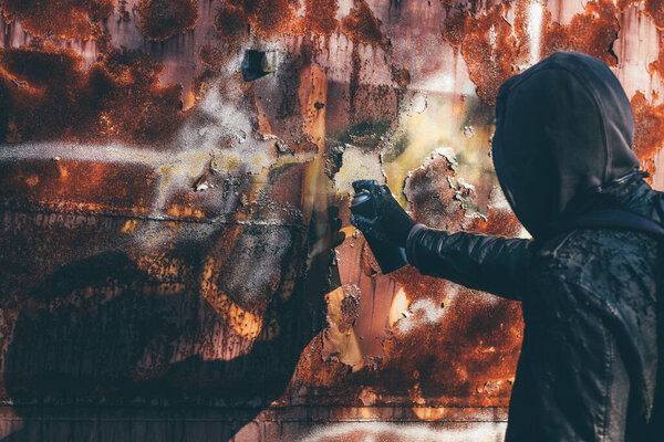 Бездомный рисует старый вагон аэрозолем. Неузнаваемый мужчина в концептуальном образе с избирательным фокусом.