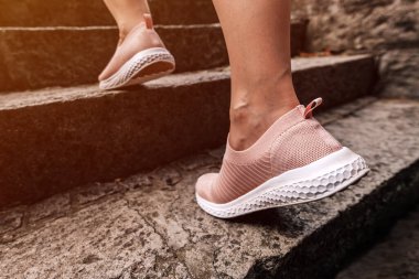 Kadın koşucu parkta merdivenlerden koşarak antrenman için ısınıyor, seçici odak noktasını hareket bulanıklığı efektiyle kapatıyor