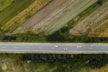 Yoldaki üç beyaz araba, İHA pov 'un üstünden aşağıya doğru hava manzaralı.