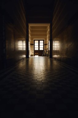 Eski binanın boş koridoru bisiklet siluetiyle aydınlığa çıkıyor. Seçici odak.