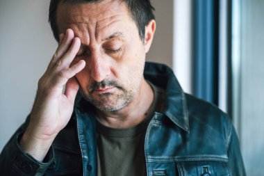 İçki içtikten sonra baş ağrısından muzdarip, acı içinde kıvranan yetişkin bir adam. Seçici odak.