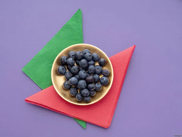 Friska superfood blåbär på färgstarka bakgrund med pappersservetter, servetter och guldplätering. — Stockfoto