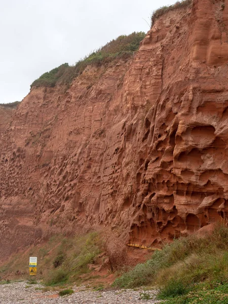 Erozyon kırmızı kumtaşı kıyı kayalıklardan Budleigh Salterton, Devon, İngiltere'de ve ıssız Çıplaklar Plajı başlangıcı. — Stok fotoğraf