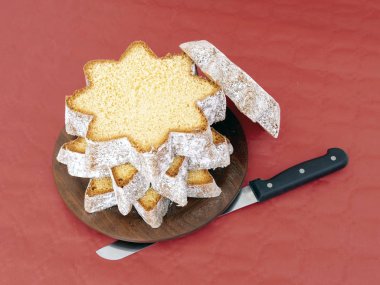Sliced pandoro, Italian sweet yeast bread, traditional Christmas treat. With knife on red. Overhead flat lay view. clipart