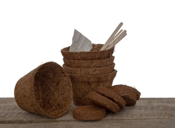 Vasi di cocco e compost compresso con semi ed etichette in legno. Giardinaggio primaverile ecologico. Isolato su sfondo bianco . — Foto Stock
