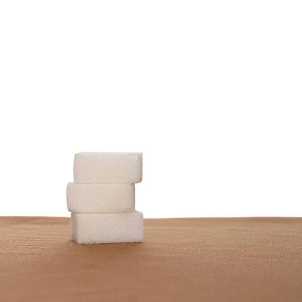 Pila di tre zollette di zucchero su tessuto, sfondo bianco. Note di alimentazione . — Foto Stock