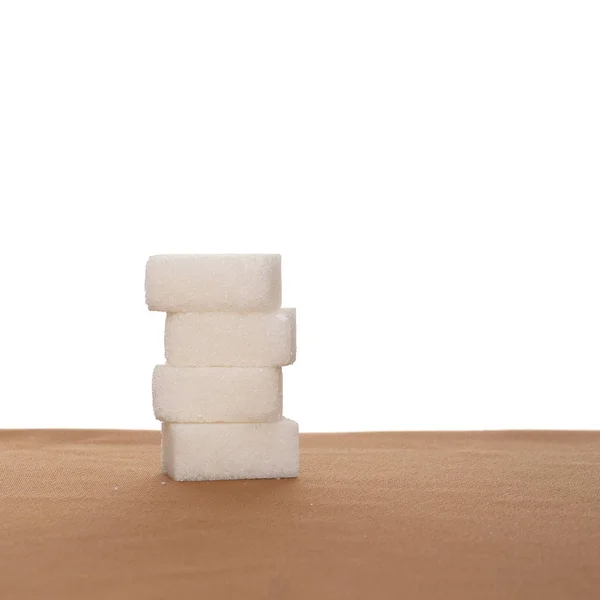 Pile de quatre cubes de sucre sur tissu, fond blanc. Une alimentation saine . — Photo