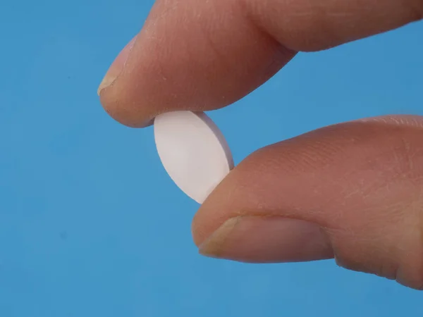 Natriumalendronat-Tablette zwischen den Fingern, ein nicht hormonelles Medikament zur Behandlung der postmenopausalen Osteoporose bei Frauen. Stockbild