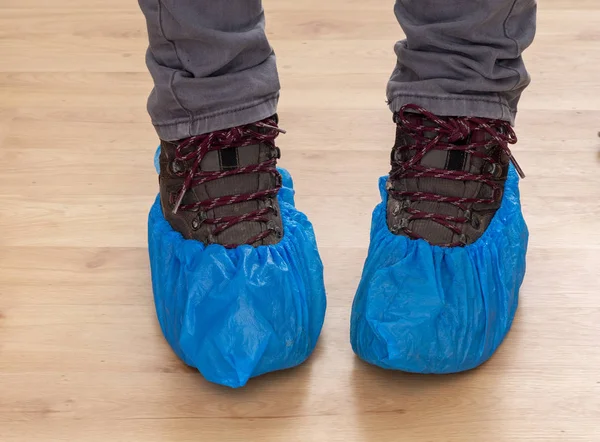 Botas de paseo y pies en protectores de zapatos de plástico azul, fundas. Higiene en situaciones médicas, etc. Uso único, desechable . — Foto de Stock