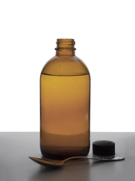 Brun glasflaska vintage medicin med sked. Isolerad mot vit bakgrund. Top som tas bort. — Stockfoto