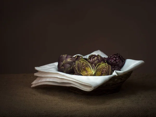 Alcachofras cruas, legumes mediterrânicos, não cozidos em cesta no hessian rústico, Natureza morta, pintura leve com textura . — Fotografia de Stock