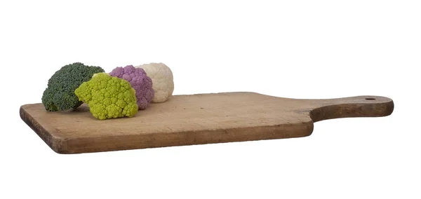 Buntes Gemüse auf einem hölzernen Schneidebrett, isoliert auf weiß. roher Blumenkohl, violett, weiß und grün, mit frischem Brokkoli. Gesundes Sortiment. Stockbild