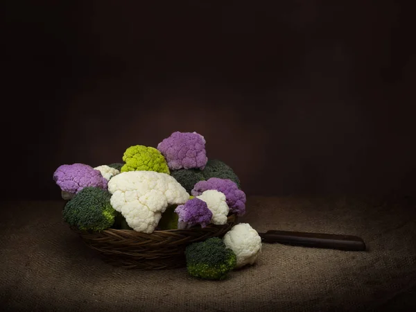 Legumes naturalmente coloridos na cesta, estilo chiaroscuro vida morta escura. Couve-flor crua variada, com flores de brócolis. Sortimento saudável . — Fotografia de Stock