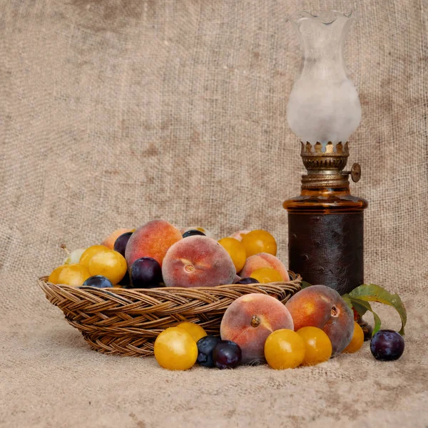 Old fashioned heritage fruit from a long abandoned orchard in an old wicker bowl, with vintage oil lamp on hessian. Still life. — Stock Photo, Image
