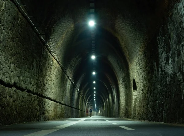 Fussgängerradweg zwischen levanto und framura, in der nähe von cinque terre, ligurien, italien. Zwei unbekannte Wanderer in der Kühle eines alten Eisenbahntunnels. Stockbild