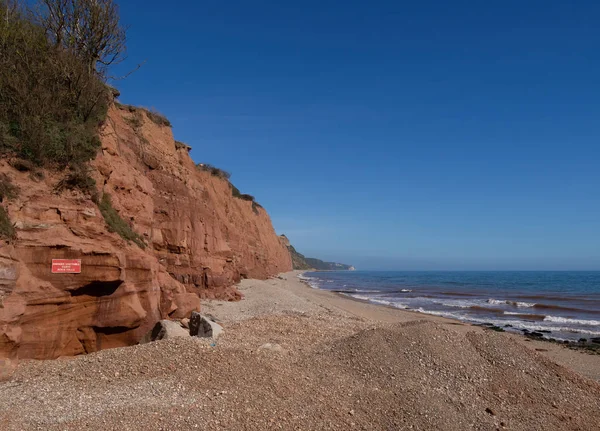 Sidmouth, Devon, İngiltere'deki ünlü Jurassic Coast kırmızı kayalıkları. Heyelan tehlikesi uyarısı ile Sidmouth Beach Doğu arıyorsunuz. — Stok fotoğraf