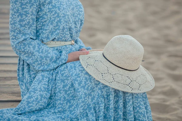 modest girl in a hat near the seashore on the beach, against the blue sky
