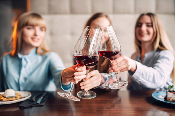 portrait of three female friends drinking red wine, young women celebrating in cafe