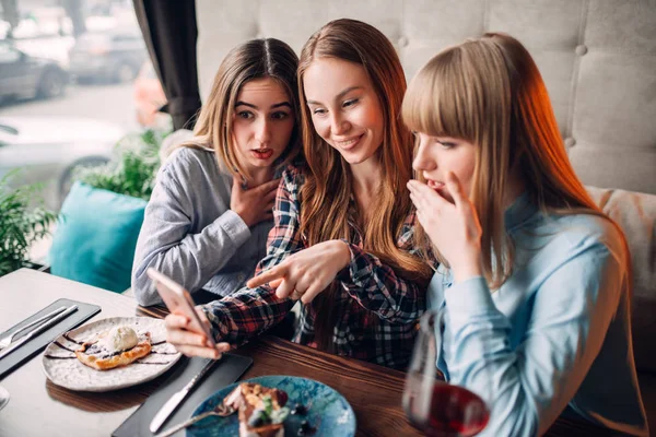Üç kadın arkadaş telefonu kafede fotoğraflarına bakmaktan