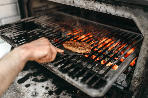 グリル オーブンで煙のような肉を焼く男性料理ハンバーガーの調理 — ストック写真