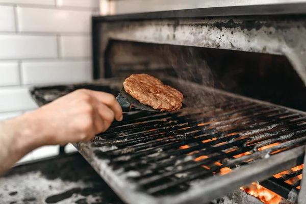 グリル オーブンで煙のような肉を焼く男性料理ハンバーガーの調理 — ストック写真