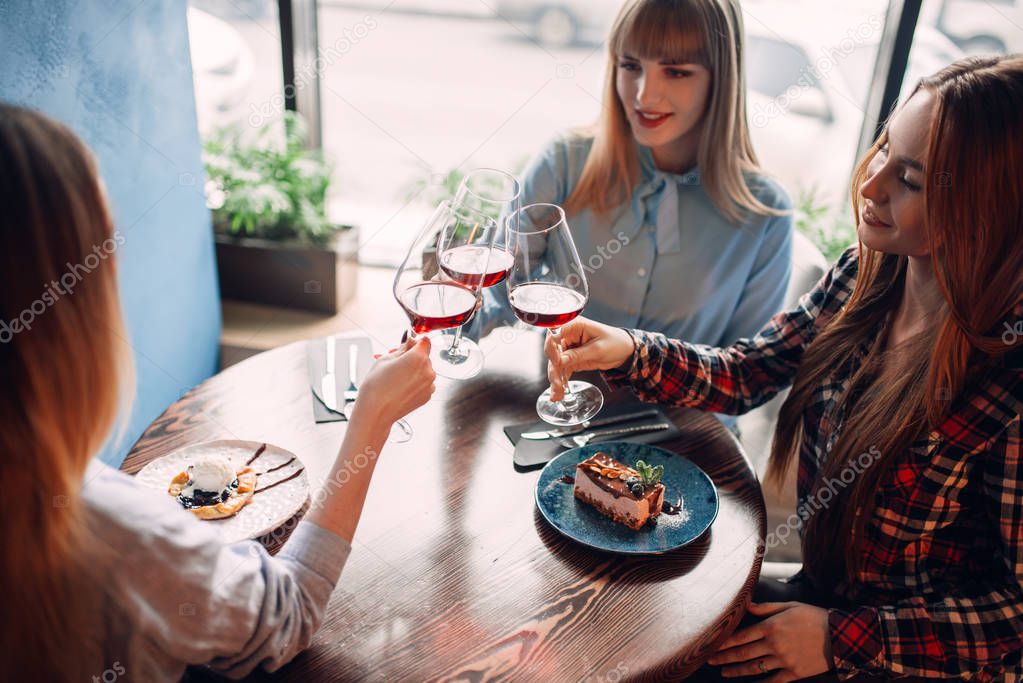 portrait of three female friends drinking red wine, young women celebrating in cafe