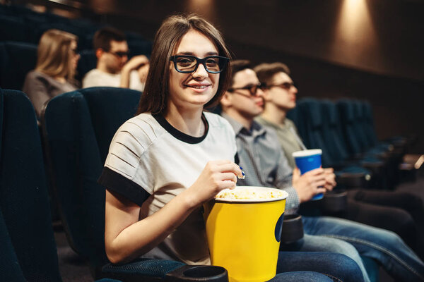 Молодая женщина в 3D очках с попкорном сидит на сиденье в кинотеатре. Showtime, просмотр фильмов
 