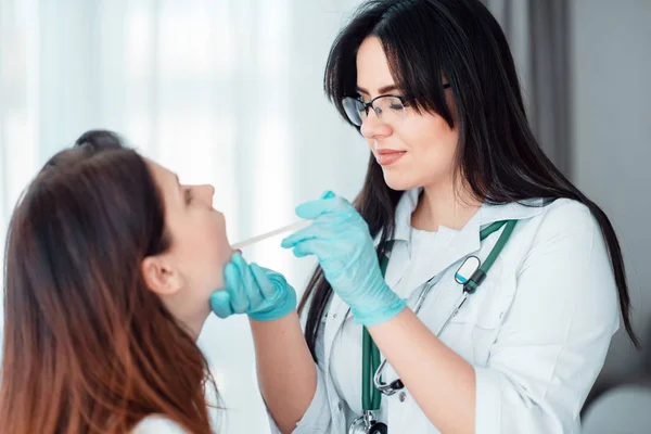 young woman at family doctor, specialist examining throat of female patient