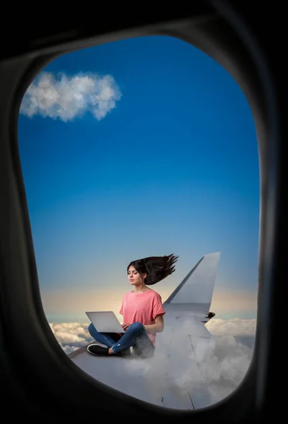 飛行機の翼の上に座ってラップトップを持つ女性 — ストック写真