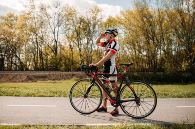 Bisikletçi kask ve spor giyim, üzerinde eğitim cyclocross yol asfalt. Erkek sporcu üzerinde bisiklet ile gidiyor. İş günü bisiklet yolu