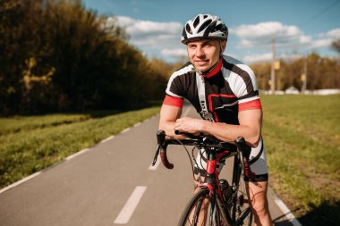 Kask ve spor giyim, bisikletçi eğitim asfalt yolda Bisiklete binme. Erkek sporcu üzerinde bisiklet ile gidiyor. İş günü bisiklet yolu