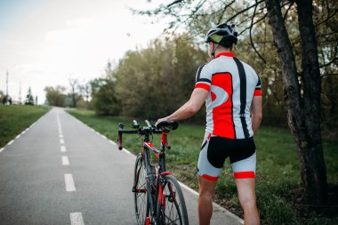 Kask ve spor giyim bisikletçi bisiklet üzerinde arkadan görünüm ile gidiyor. Bisiklet yolu, egzersiz Bisiklete binme