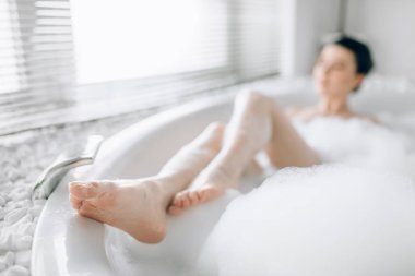 köpük banyosunda yalan ve gösterilen legs, gevşeme, sağlık ve cilt bakımı kavramı çekici kadın