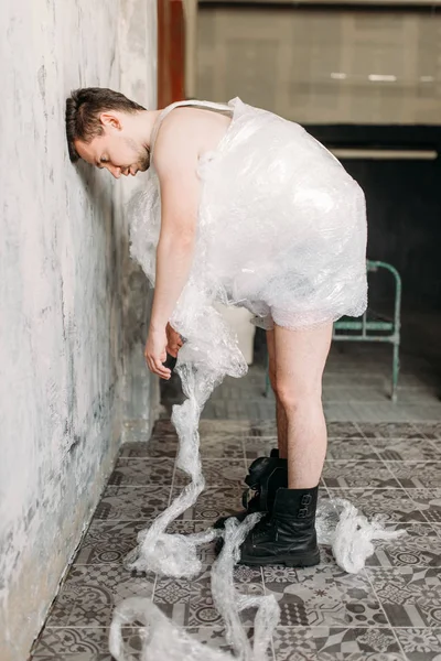 裸怪胎男子裹在包装膜摆在垃圾室内部 — 图库照片